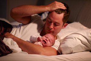 Vater mit weinendem Baby im Bett