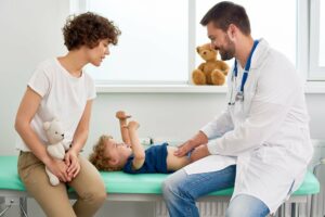 Kinderarzt tastet den Bauch eines Jungen in einer Untersuchung ab