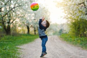 ein kleiner Junge spielt mit einem bunten Ball
