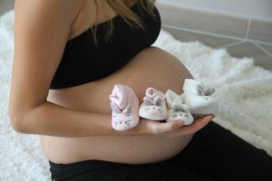 schwangere mit zwei paar babyschuhen auf dem bauch