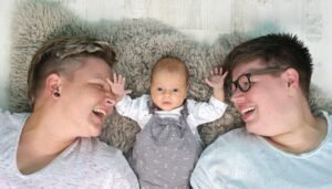 Zwei Frauen liegen mit ihrem Baby zusammen auf einem Fell