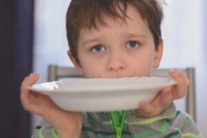 hungriges Kind zeigt einen leeren Teller