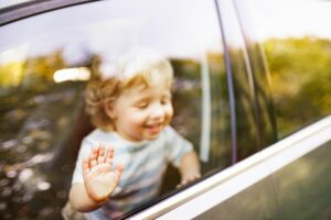 Kind steht am Fenster im Auto