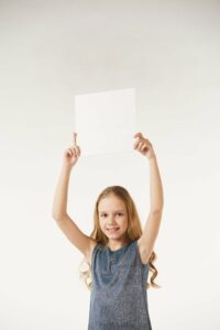 ein kind haelt ein weisses blatt papier in die luft