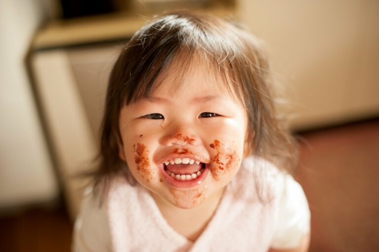 Kind lacht und hat Essen im Gesicht