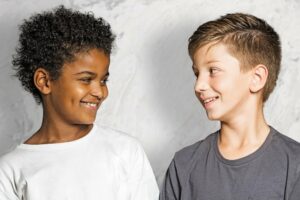 zwei Kinder mit unterschiedlicher Hautfarbe lächeln einander an