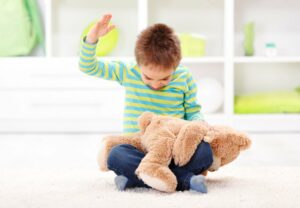 Ein Junge schlägt seinen Teddybär