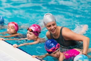 grundschullehrerin hilft kindern beim schwimmunterricht
