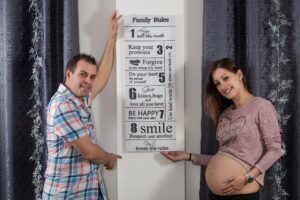 Schwangere Frau und ihr Mann hängen Familienregeln auf