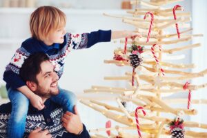Kind schmückt mit Vater Weihnachtsbaum