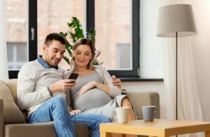 ein mann und seine schwangere frau schauen gemeinsam auf ein smartphone
