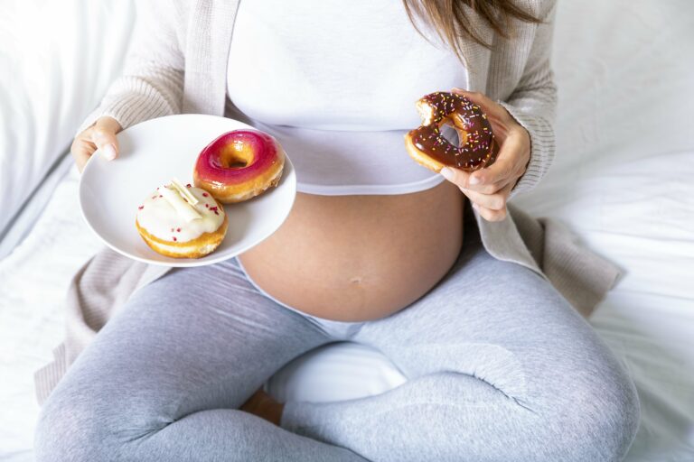 Schwangere Frau isst Donuts