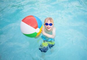 kleines Kind mit einem Wasserball im Schwimmbecken