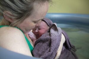 mutter haelt ihr neugeborenes Baby inach einer wassergeburt in den armen