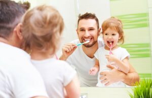 Vater putzt zusammen mit seiner Tochter die Zähne